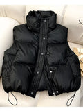 Black quilted puffer vest with snap buttons and drawstring hem on cream sofa