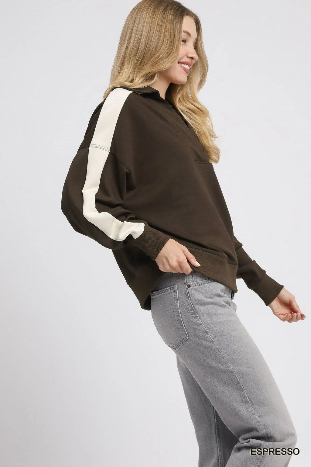 Side view of model in brown cream striped polo showing relaxed fit and ribbed cuffs