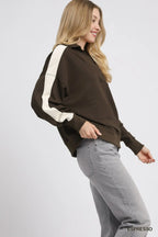 Side view of model in brown cream striped polo showing relaxed fit and ribbed cuffs