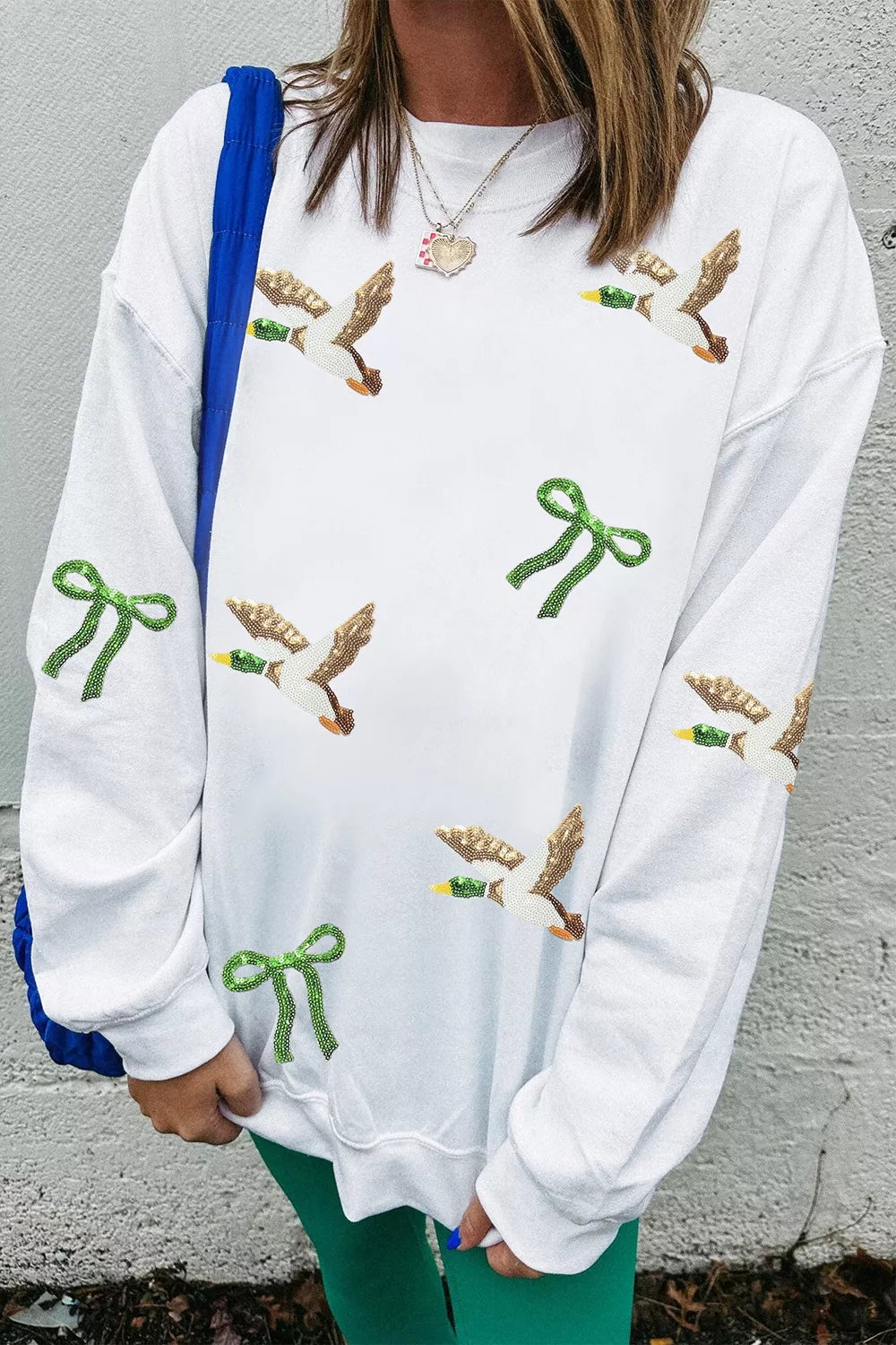Pull oversize blanc canards pailletés porté avec pantalon vert mur gris