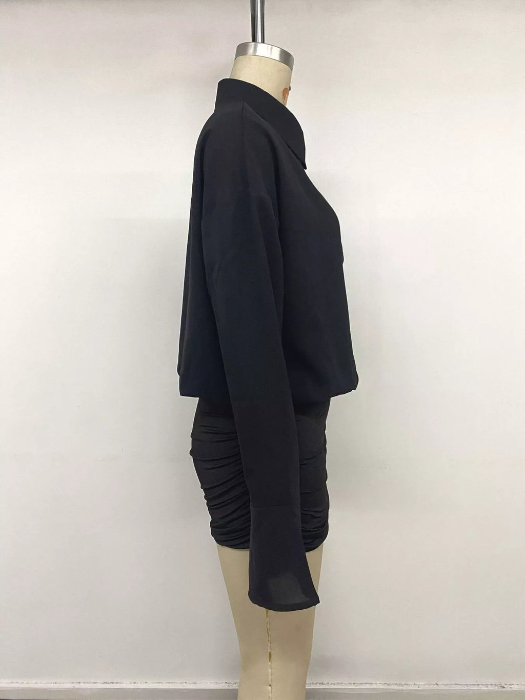 Profil latéral mannequin robe noire : corsage ample, manches fluides et fronces serrées