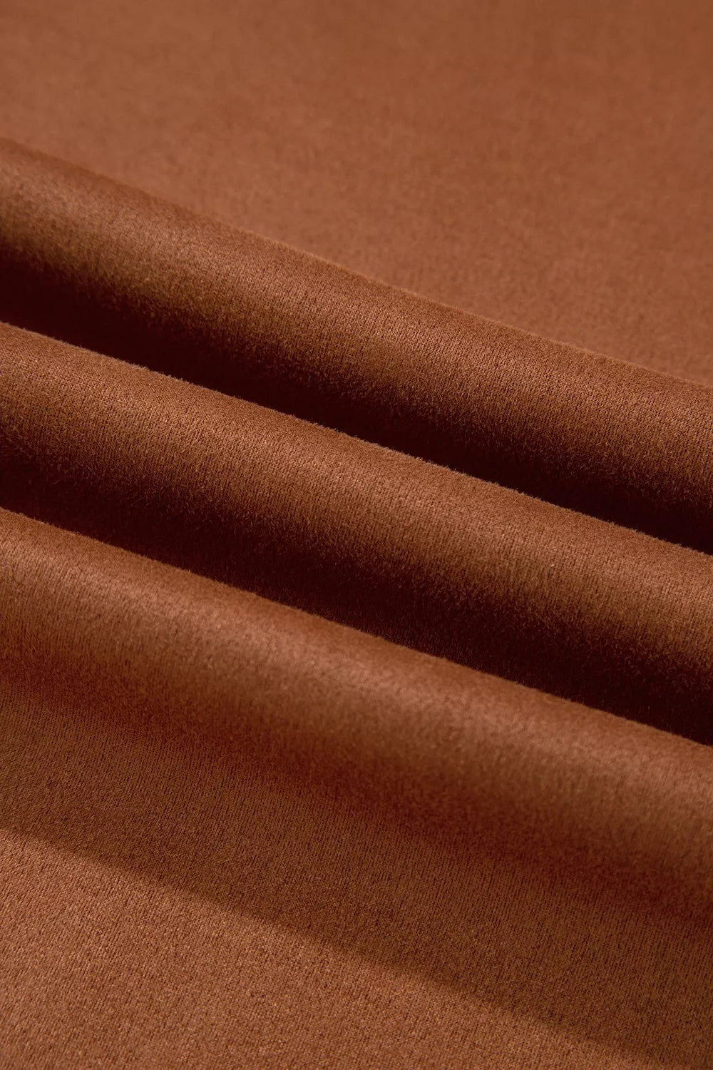 Makrotextur des weichen, glatten rostbraunen Stoffes in sanften Wellen, erdiger Farbton