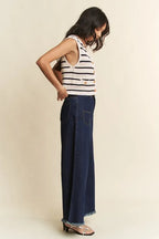 Side profile of model wearing navy cream striped vest with gold buttons and dark blue wide-leg frayed jeans