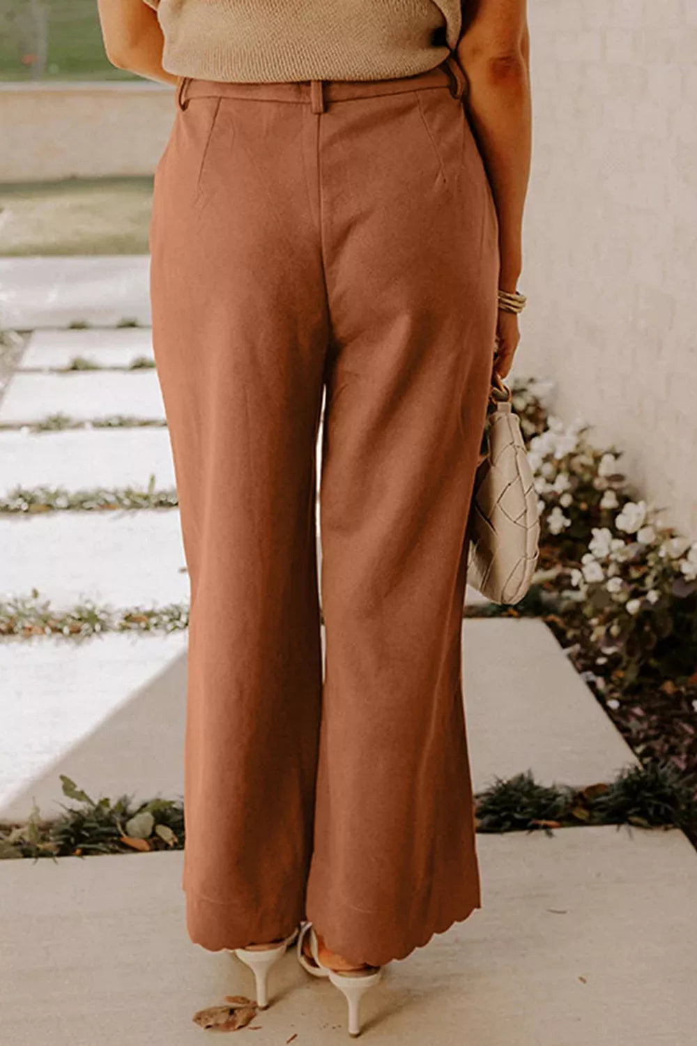 Terrakotta-farbene Schlaghosen mit gezackter Kante, drapierter Stoff, beige Top und Sandalen
