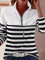 Woman in black and white striped quarter zip t-shirt with silver zipper and blue jeans