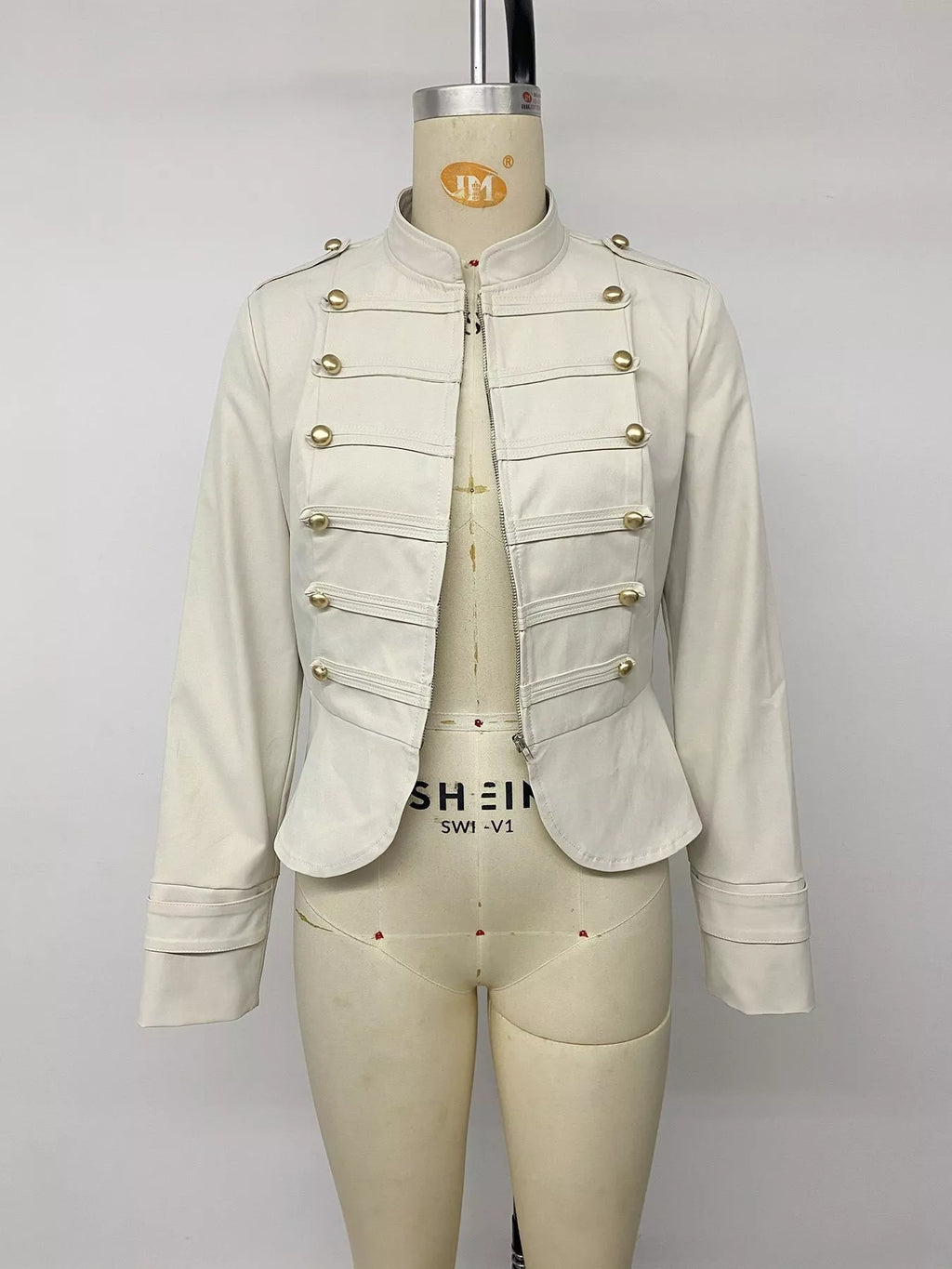 Veste cropped couleur crème sur mannequin avec zip ouvert révélant les sangles de pression ton or