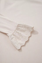Macro shot of flared sheer eyelet lace ruffle cuff attached to ribbed sleeve