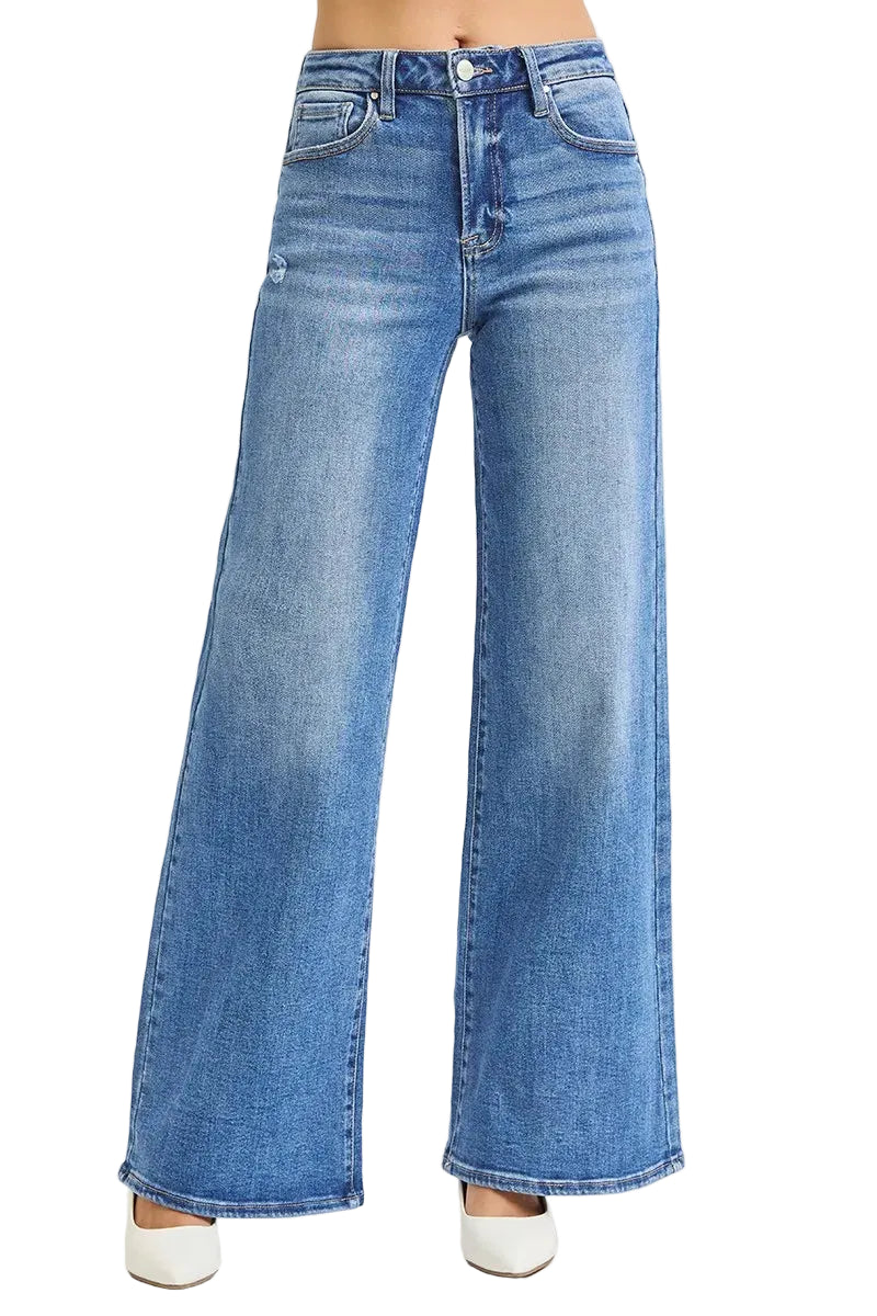 Medium blue high-rise wide-leg jeans with five pockets and thigh distressing, worn with white platform heels on white
