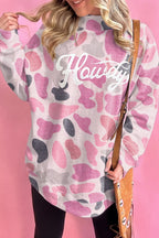 Pink camo sweatshirt styled with brown suede fringe bag against solid pink background