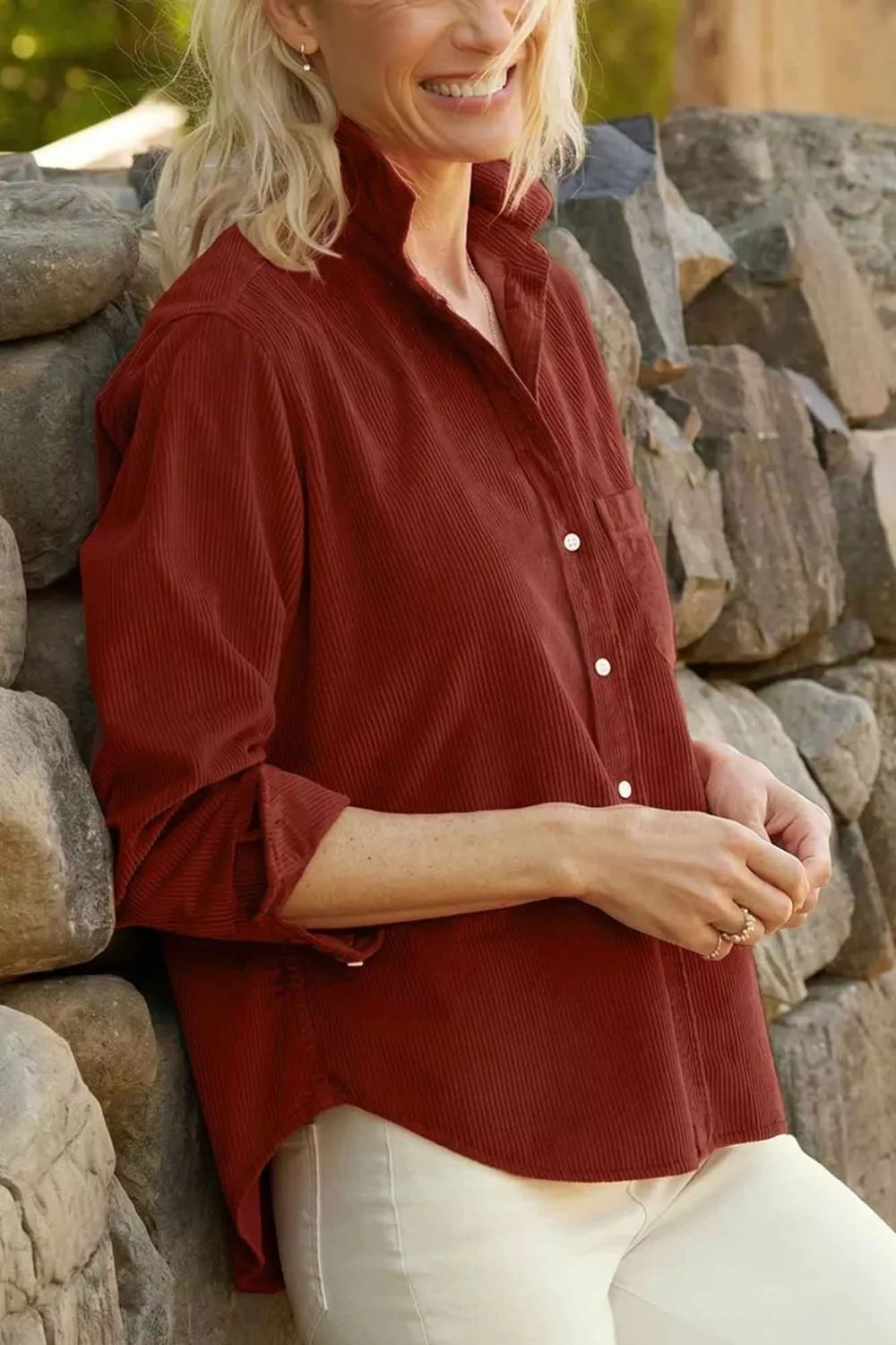 Side profile of loose silhouette rust polyester shirt with rolled adjustable cuffs