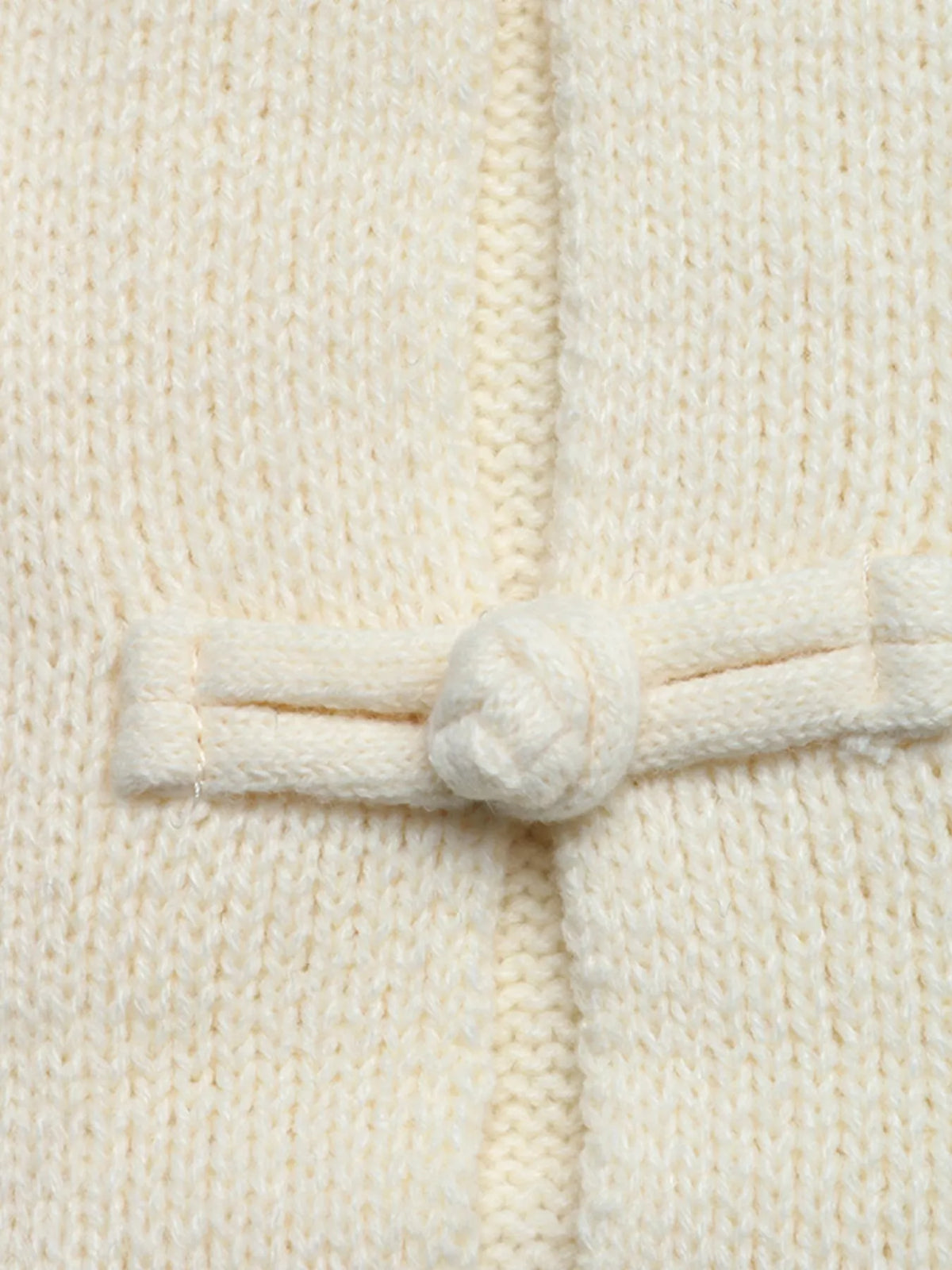 Extremnahaufnahme des filigranen, handgemachten Chinesischen Knotenknopfes an der Vorderseite der Strickjacke