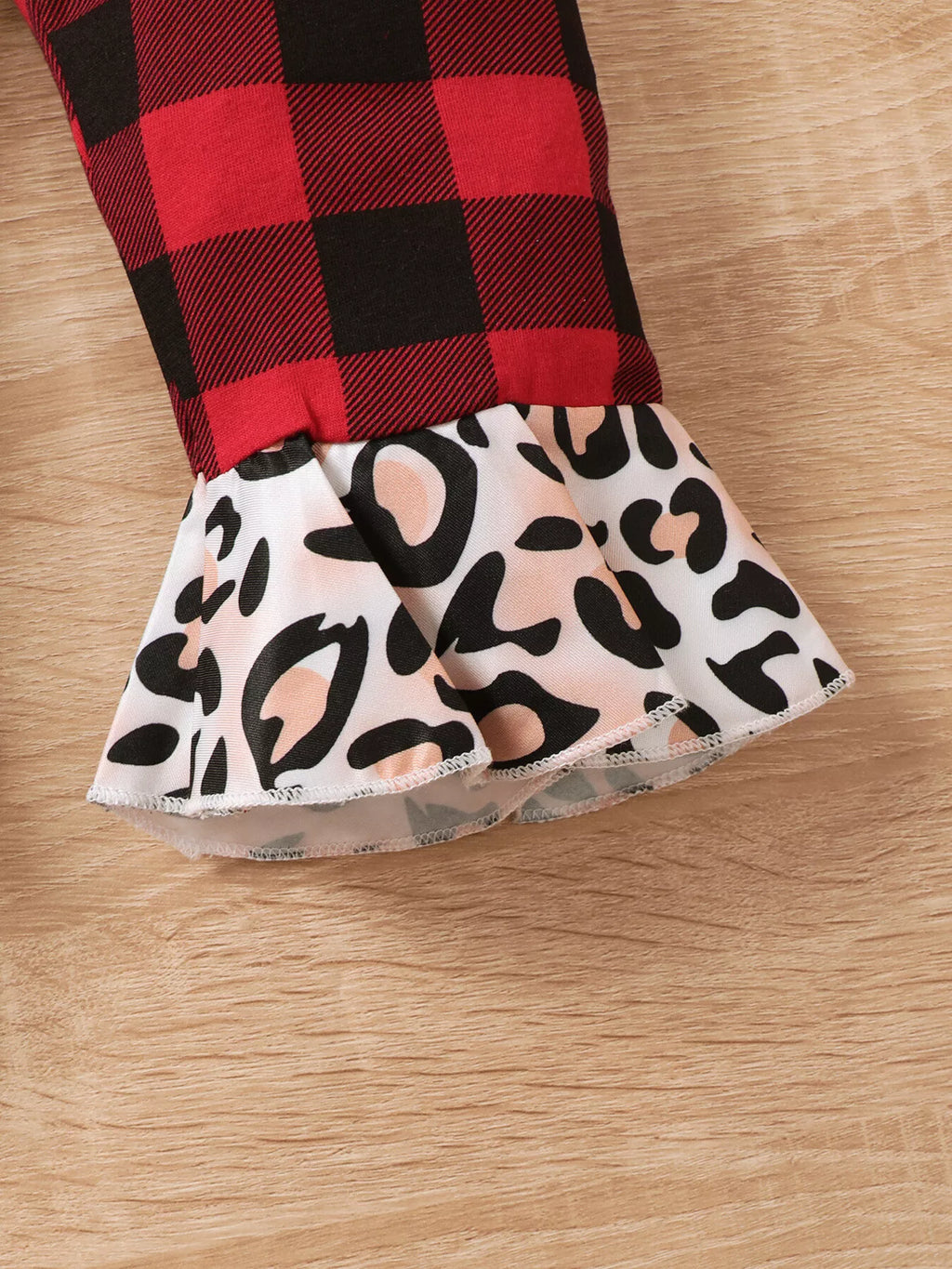 Bajo acampanado con volante en la pernera hecho de tela blanca con estampado leopardo negro y beige unido al tejido a cuadros
