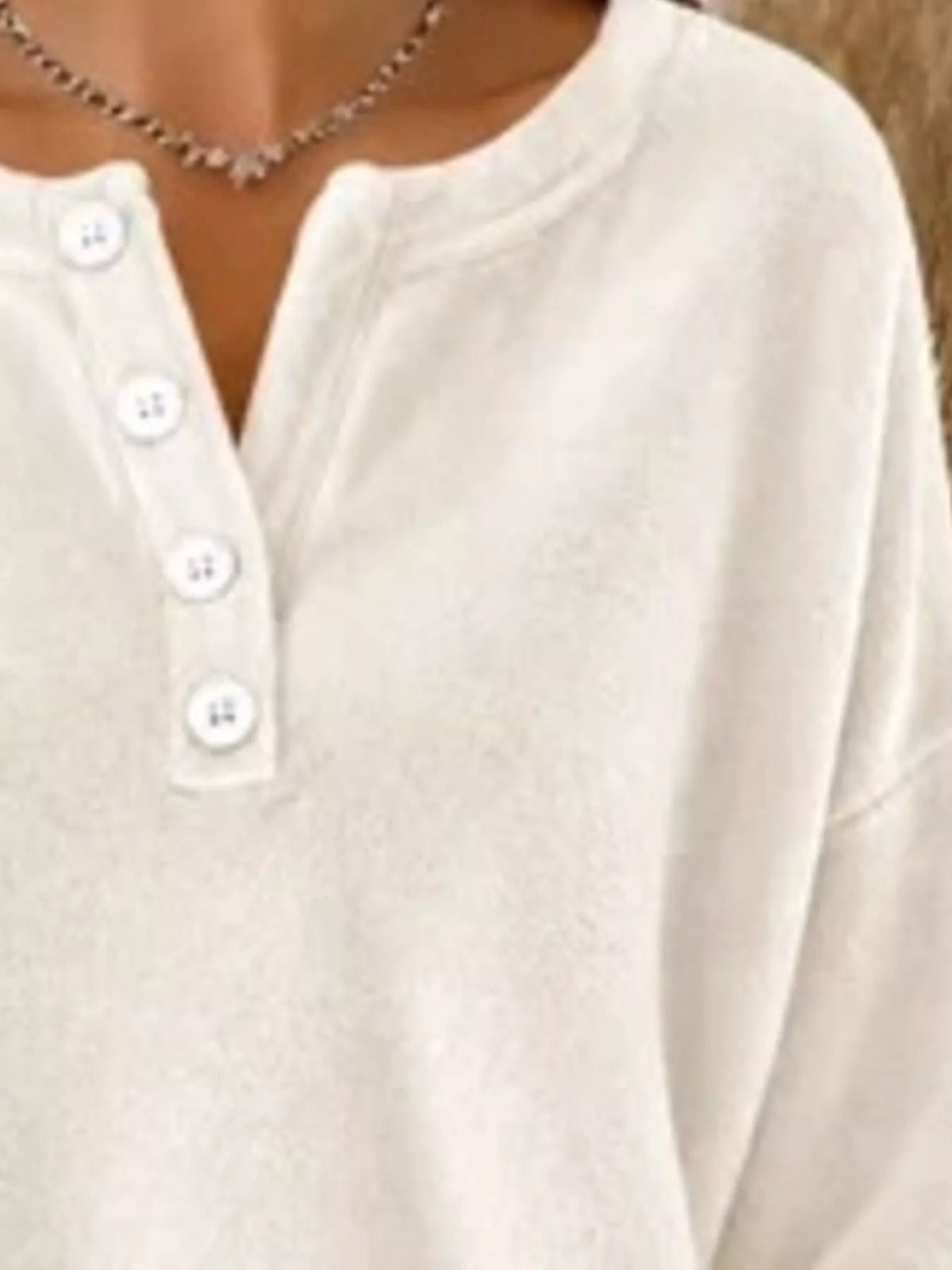 Close-up of white sweatshirt fabric texture, rounded neck, and aligned white buttons