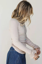 Model adjusting ruffled lace cuffs, highlighting drape of stretchy viscose fabric