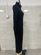 Profil latéral d'une robe pull tricotée côtelée noire sur mannequin soulignant l'élasticité, la profondeur du col V et l'ourlet midi droit