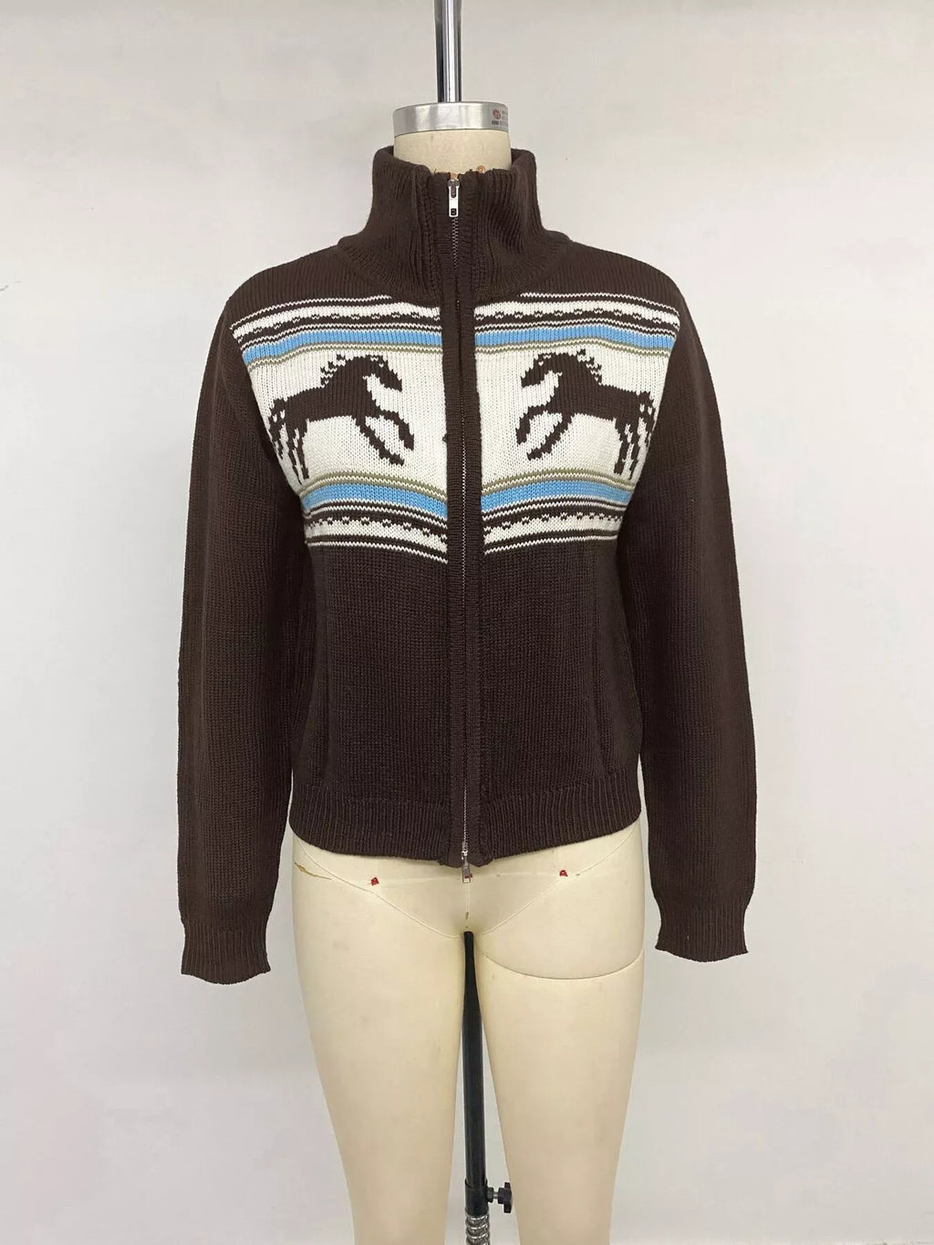 Frontalansicht am Mannequin: dunkelbraune Zip-Up-Jacke mit hohem Mock-Neck, silbernem Reißverschluss und Fair-Isle-Pferdemotiv
