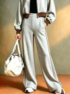 Pantalones anchos grises con franjas laterales distintivas combinados con zapatillas voluminosas