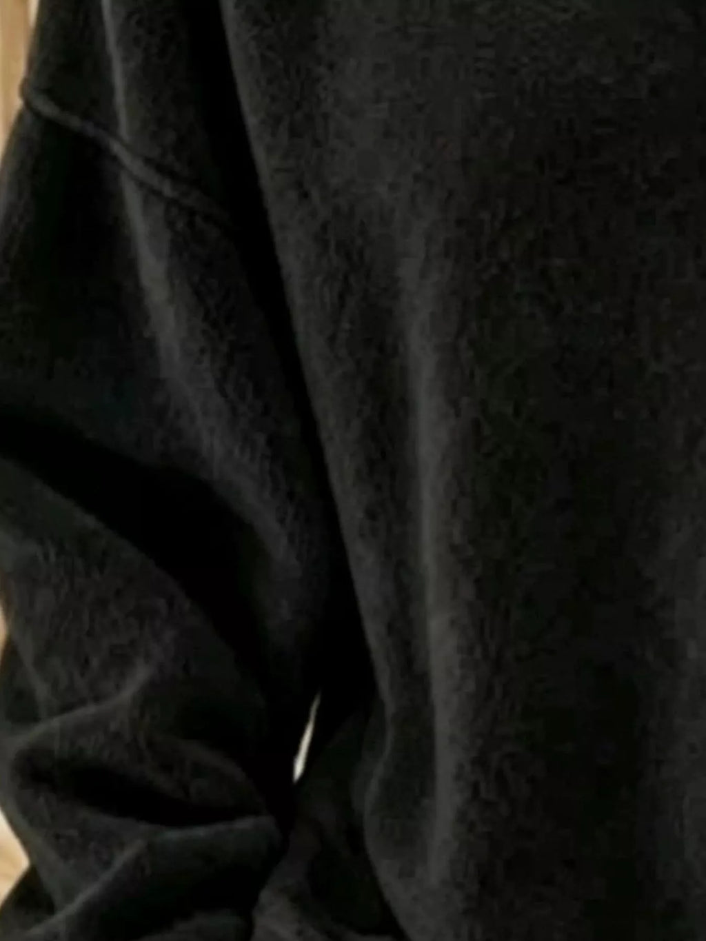 Macro shot of black sweatshirt soft textured fabric and dropped shoulder seam stitching