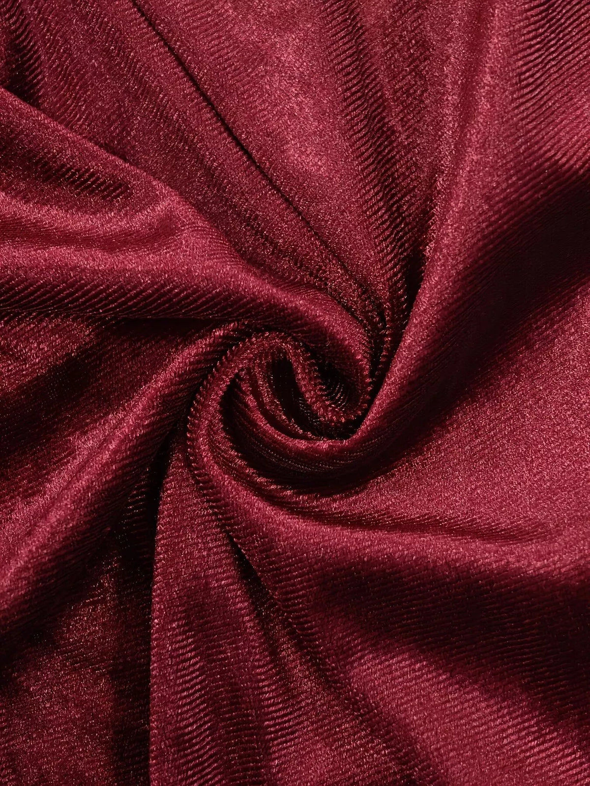 Macro du matériau velours stretch sombre tourbillonnant révélant sa texture côtelée et sa surface réfléchissante