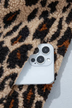 Flat lay of high-pile leopard print jacket covering smartphone to show scale and thick plush texture