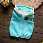 Top-down photo of light blue hooded vest on wood surface showing silver zipper, quilting lines, and patch