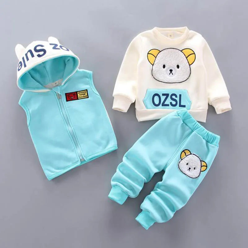 Flat-lay of light blue children's set with zip-up vest, fuzzy bear sweatshirt, and jogger pants emblem