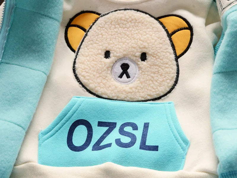 Macro view of cream sweatshirt chest with high-pile beige bear applique and blue OZSL printed pocket