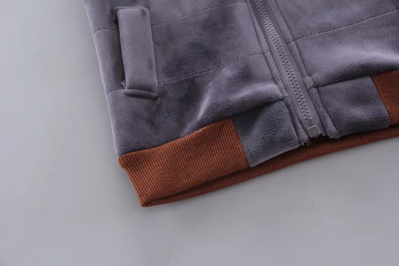 Detail shot of grey quilted fleece garment hem showing vertical zipper and contrasting brown ribbed cuffs