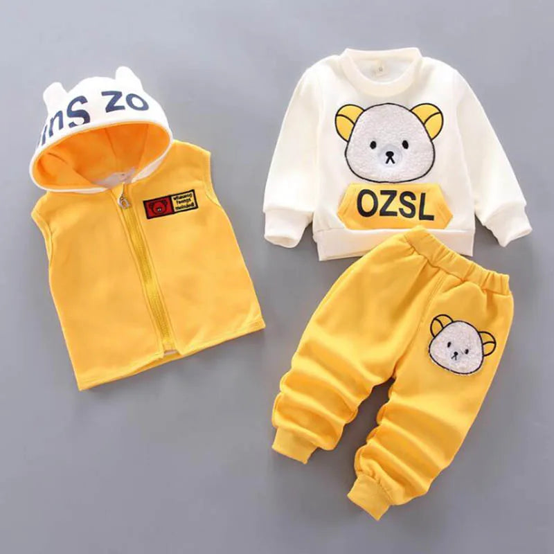Flat lay of yellow and white children's outfit including bear-ear vest, graphic sweatshirt, and patched pants
