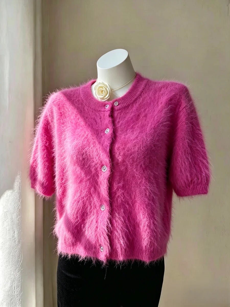 Cardigan curto de pelúcia rosa vivo em manequim com gola redonda e botões brancos, enfatizando textura suave semelhante a pelos