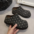 Kohlegraue Filz-Mules mit cremefarbenen Punkten und schweren schwarzen Sohlen, in der Hand gehalten für den gemütlichen Winter-Look
