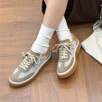 High-angle view of sneakers crossed at ankles, highlighting mesh texture, olive overlays, and rubber sole