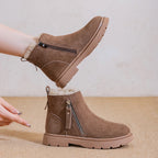 Bota de ante vacuno marrón sostenida para mostrar perfil de suela gruesa de goma, entrada con cremallera diagonal y estructura plana cómoda