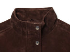 Detalhe da gola alta levantada da jaqueta castanha-escura com textura suave estilo suede e botões de pressão prateados.