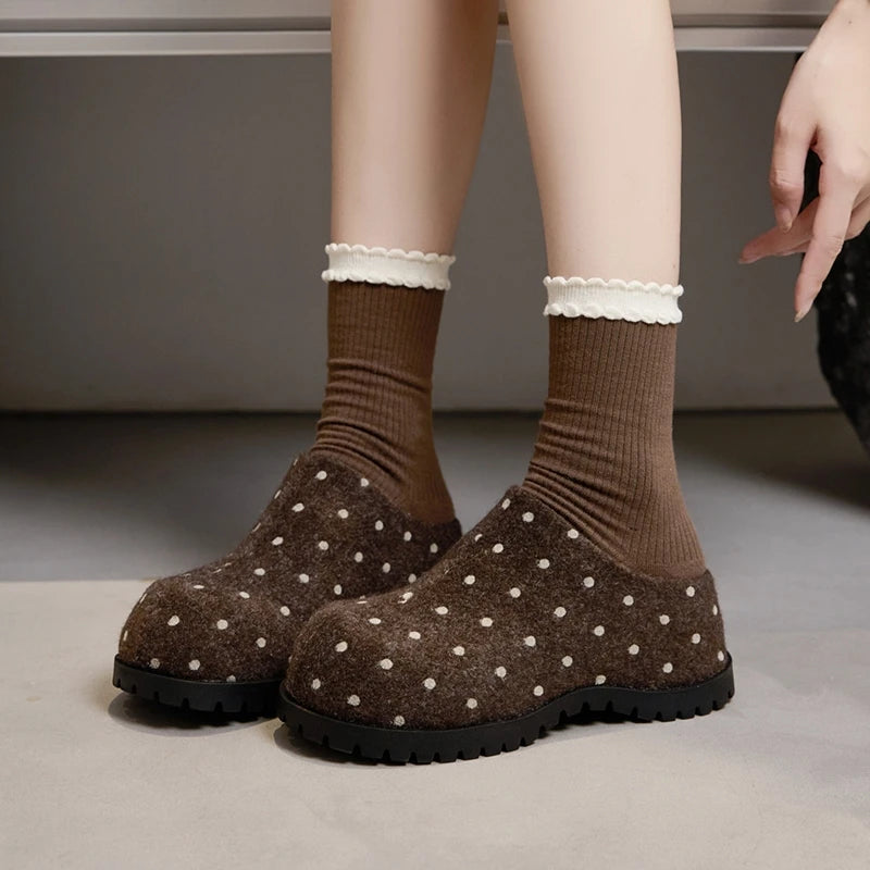 Braune Mule-Clogs mit weißen Punkten kombiniert mit gerippten Socken mit gewellten Spitzenkanten, ruhend auf dicker schwarzer Sohle