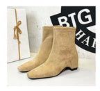 Beige Wildlederschnürsenkel-Stiefel nebeneinander: weiches Flock-Obermaterial, sichtbare Nähte am Zehenkasten und niedriger Absatz.