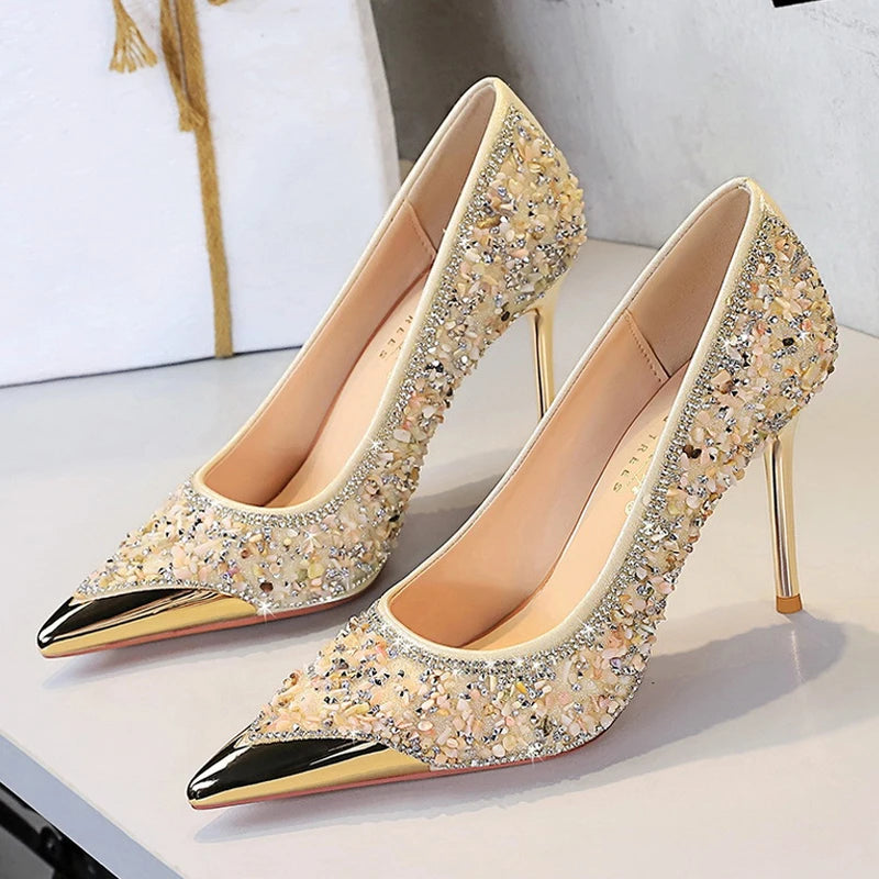 Nahaufnahme von nude Stilettos mit dichtem Glitzer-Beads und poliertem Goldspitz