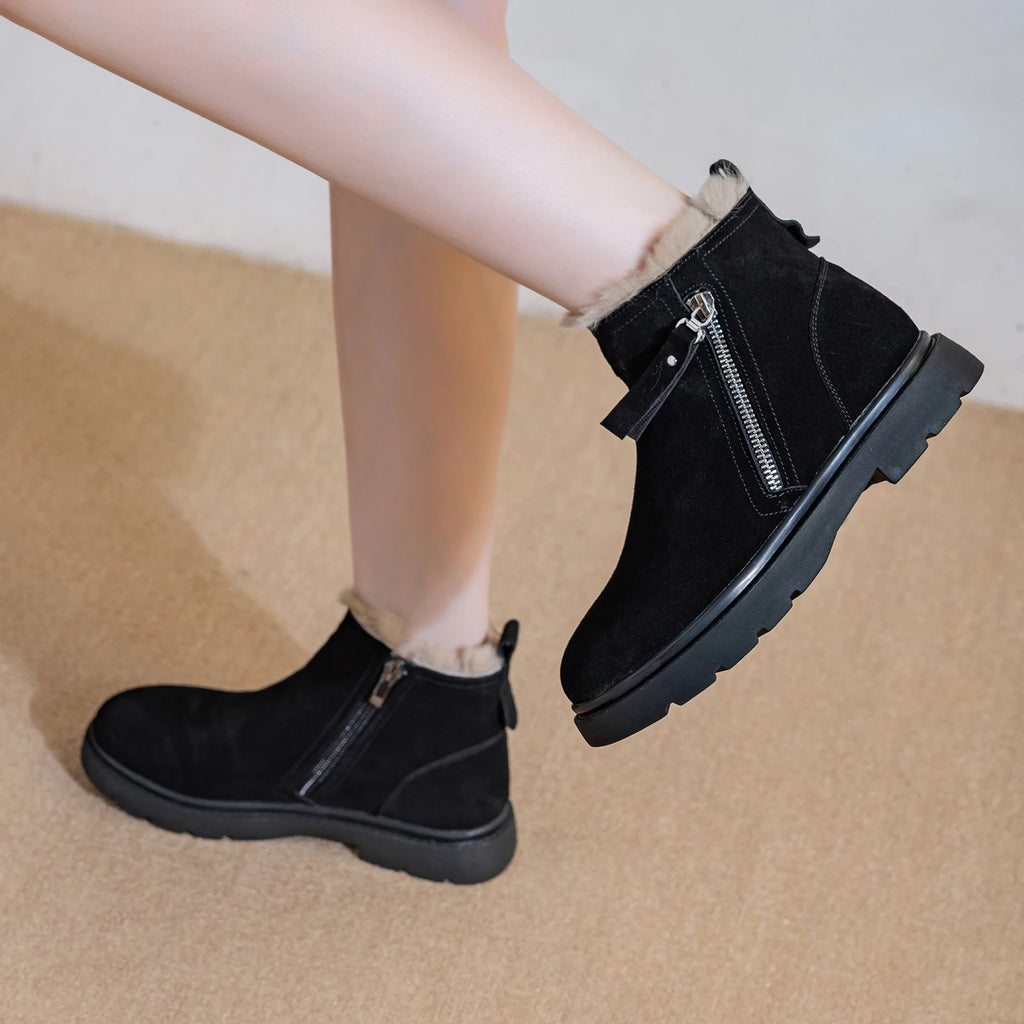 Perfil lateral de piernas de modelo en botas de invierno de ante negro con suela de plataforma y cremallera plateada al dar un paso
