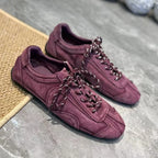 Burgundy flat sneakers on woven mat edge showing anti-slip sole and matte finish