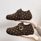 Par de zapatillas slip-on marrones con lunares y hebilla dorada mostrando punta redonda