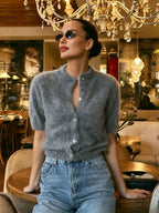 Mulher com cardigan curto felpudo cinza aberto para decote em V, combinado com jeans e óculos de sol sob lustre