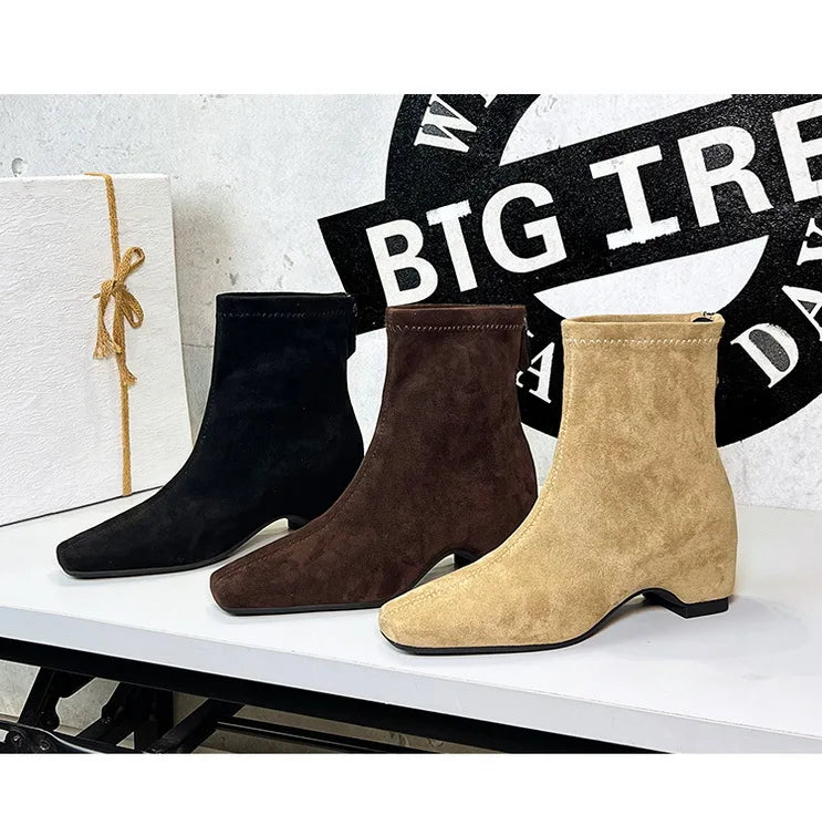 Drei Wildlederschnürsenkel-Stiefel in Schwarz, Braun und Beige diagonal angeordnet mit elastischen Schaften auf Weiß.