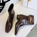 Botas curtas marrons brilhantes em PU com bico quadrado e zíper lateral sobre fundo branco