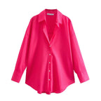 Camicia bottoni rosa acceso vista dall'alto con bottoni bianchi contrastanti e silhouette ampia