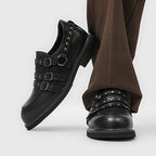 Winkelansicht schwarzer Slip-On-Schuh: abgerundete Spitze, Dreifach-Schnallenschluss, silberne Kragen-Nieten