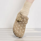 Vista lateral de zapatilla slip-on beige con lunares y hebilla dorada usada con calcetín