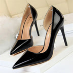 Glänzende schwarze Lackleder-pointed-toe Pumps neben flauschigem weißem Dekor, seitlicher Hohlraum und goldenes BIGTREE-Logo im Fokus