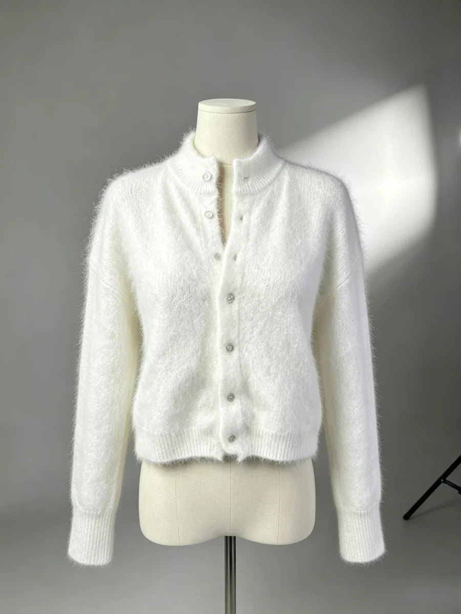 Cardigan longo branco felpudo em manequim contra fundo cinzento, destacando tecido texturizado, gola levantada e silhueta ajustada