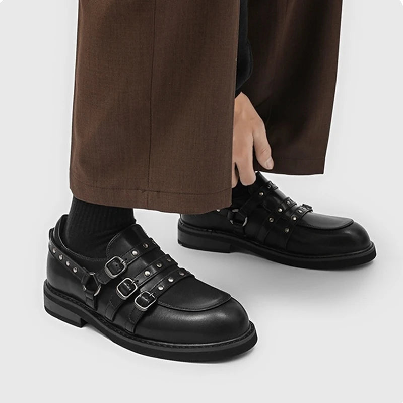 Frontalansicht schwarzer Mehrfach-Schnallen-Loafers mit Hose: symmetrische Silber-Nieten und robuste Sohle