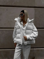 Close-up do colete branco com capuz aberto, revelando detalhe do zíper e design de gola alta